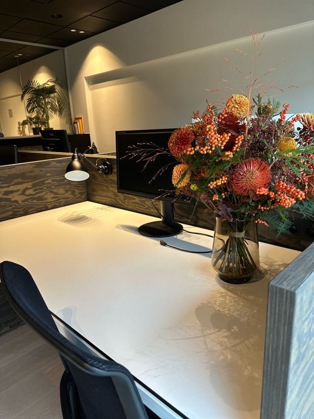 Boeket met oranje bloemen op een bureau naast de computer